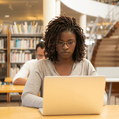 A girl working on a laptop in a library