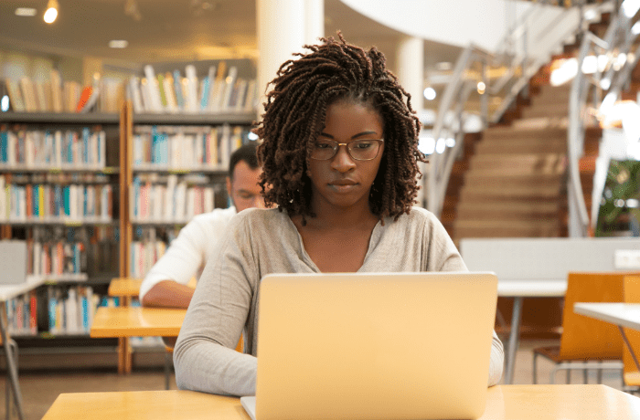 A girl working on a laptop in a library