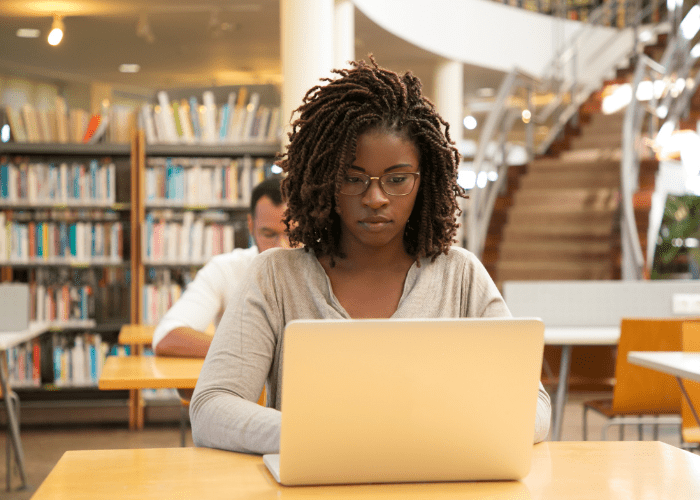 A girl working on a laptop in a library